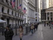 FILE - People walk past the New York Stock Exchange on March. 21, 2024. World stocks are mixed on Monday, May 13, 2024, after Wall Street coasted to the close of another winning week. U.S. futures and oil prices were higher.