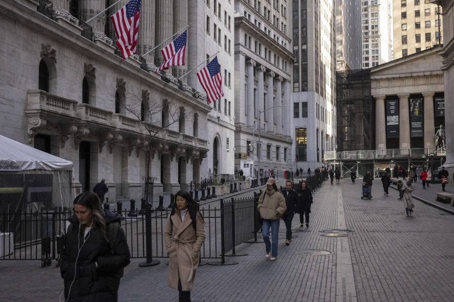 FILE - People walk past the New York Stock Exchange on March. 21, 2024. World stocks are mixed on Monday, May 13, 2024, after Wall Street coasted to the close of another winning week. U.S. futures and oil prices were higher.