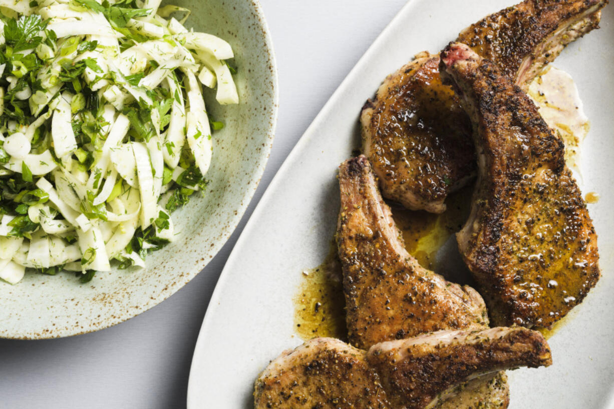 This image released by Milk Street shows a recipe for seared pork chops with fennel and herb salad.
