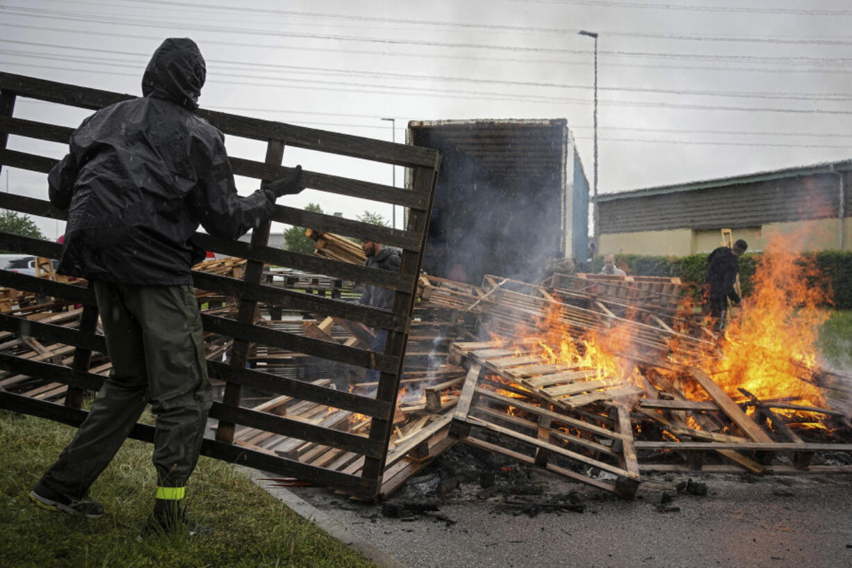 Prison workers burn wooden pallets during a protest in front of the Corbas prison, outside Lyon, France, Wednesday, May 15, 2024 . A massive manhunt was underway in France on Wednesday for an armed gang that ambushed a prison convoy, killing two prison officers, seriously injuring three others and springing the inmate they were escorting.