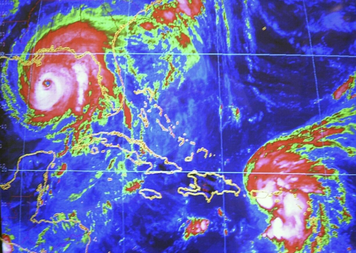 Hurricane Ivan is seen on the computer screen 250 miles from the Gulf Coast while Tropical Storm Jeanne approaches Puerto Rico on Sept. 15, 2004, at the National Hurricane Center in Miami. (J.