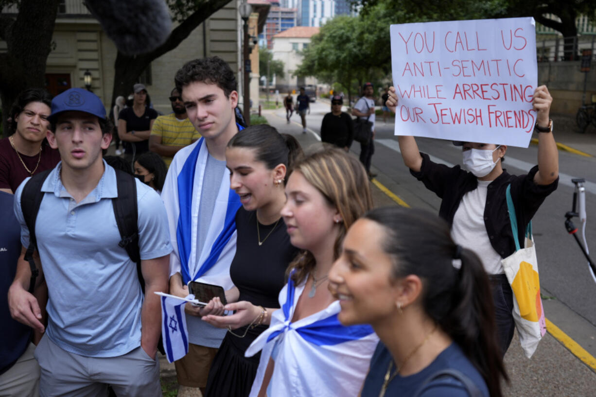 A Pro-Palestinian protester holds up a sign as Jewish students talk to the media following on campus at the University of Texas at Austin, Tuesday, April 30, 2024, in Austin, Texas.