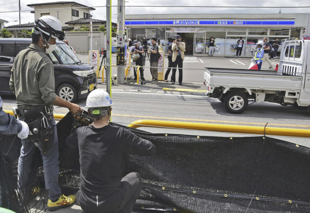 Workers set up a huge black screen on a stretch of sidewalk at Fujikawaguchiko town, Yamanashi prefecture, central Japan Tuesday, May 21, 2024. Just a few weeks ago, the town began setting up a huge black screen to block a view of Mount Fuji because tourists were crowding into the area to take photos with the mountain as a backdrop to a convenience store, a social media phenomenon known as &ldquo;Mount Fuji Lawson&rdquo; that has disrupted business, traffic and local life. (Kyodo News via AP) (Jae C.