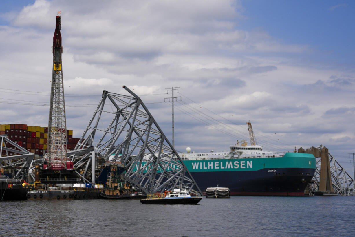 A vessel, center right, moves past the stranded container ship Dali, through a newly opened deep-water channel in Baltimore after being stuck in the harbor since the Francis Scott Key Bridge collapsed four weeks ago, Thursday, April 25, 2024.