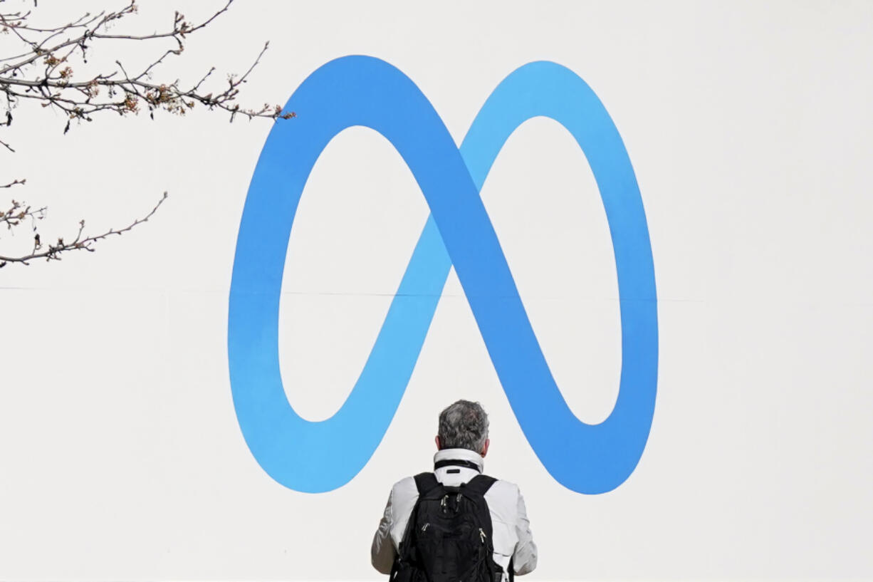 FILE - A person stands in front of a Meta sign outside of the company&rsquo;s headquarters in Menlo Park, Calif., March 7, 2023. A Delaware judge on Tuesday, April 30, 2024, dismissed a shareholder lawsuit asserting novel claims about the roles of corporate leaders and arguing that the loyalties of Meta directors and company founder Mark Zuckerberg should not lie exclusively with the social media giant.