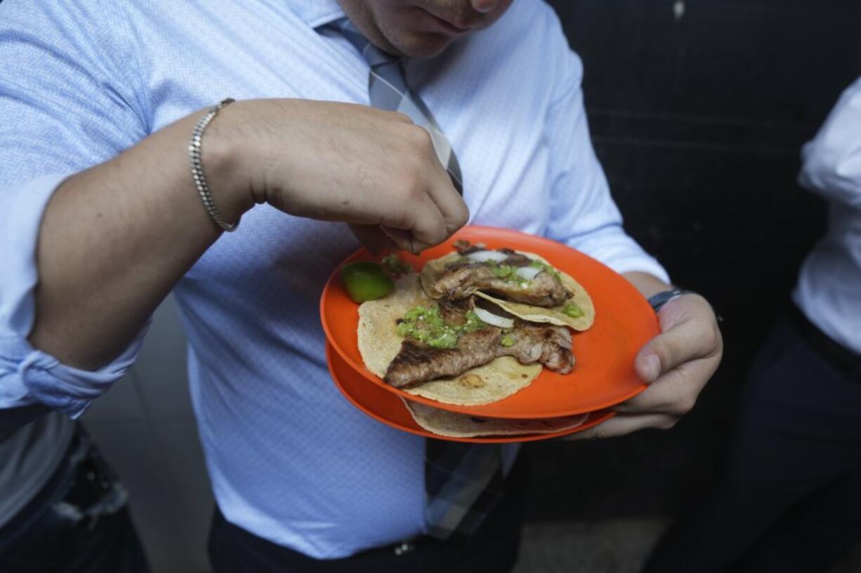 A customer finishes squeezing lime juice on his tacos Wednesday at the Tacos El Califa de Le&oacute;n stand, in Mexico City.