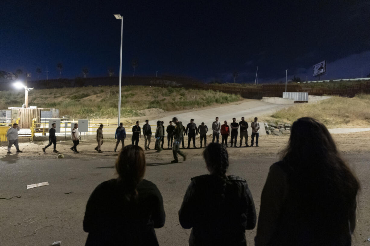 Migrants are lined up along the border walls separating Tijuana, Mexico, and San Diego, to apply for asylum with U.S authorities Tuesday, May 7, 2024, in San Diego. San Diego became the busiest corridor for illegal crossings in April, according to U.S. figures, the fifth region to hold that title in two years in a sign of how quickly migration routes are changing.