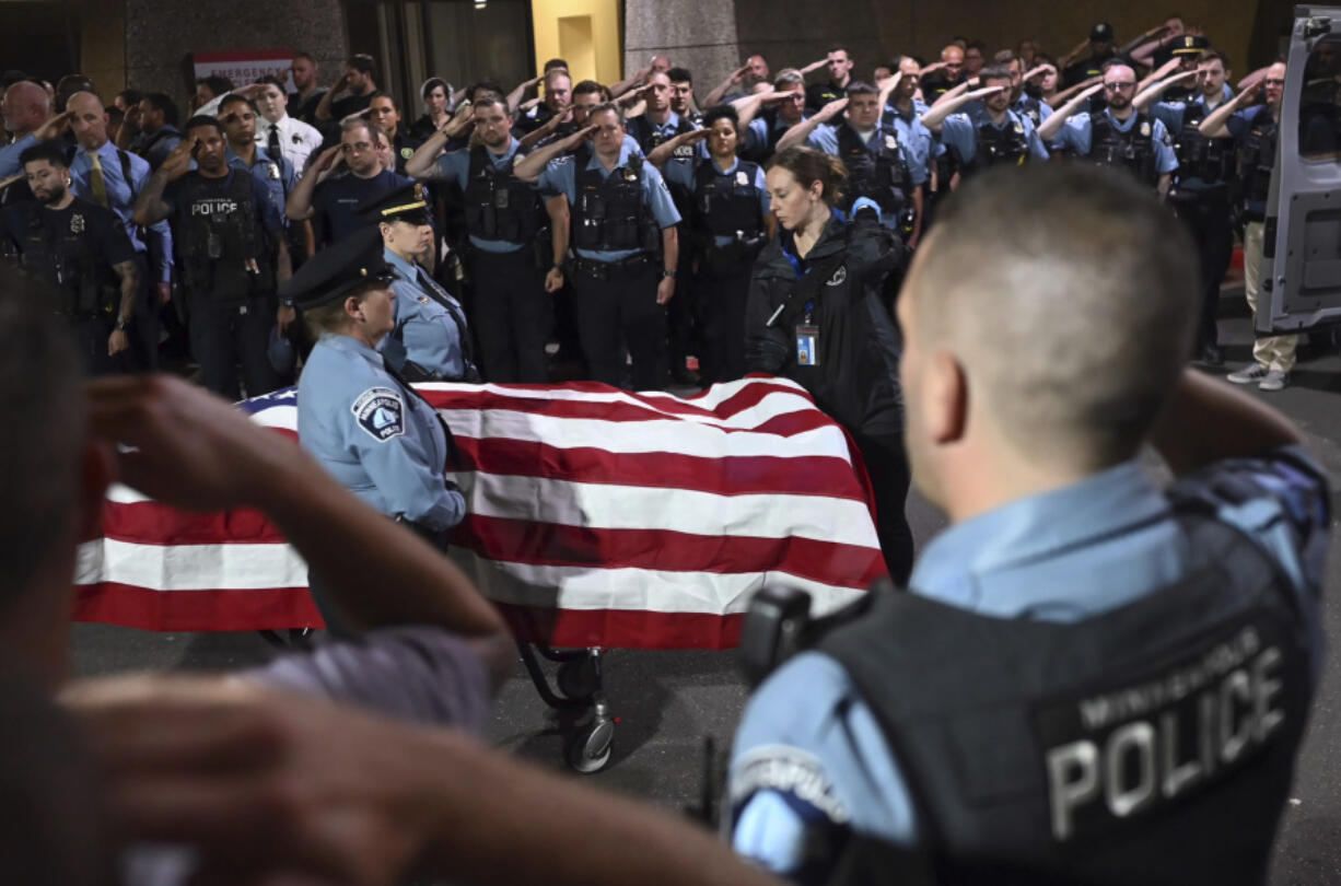 Law enforcement officers salute the body of a fallen Minneapolis officer as it is escorted to a waiting medical examiner&#039;s vehicle outside Hennepin County Medical Center in Minneapolis, Thursday, May 30, 2024, following a fatal shooting.