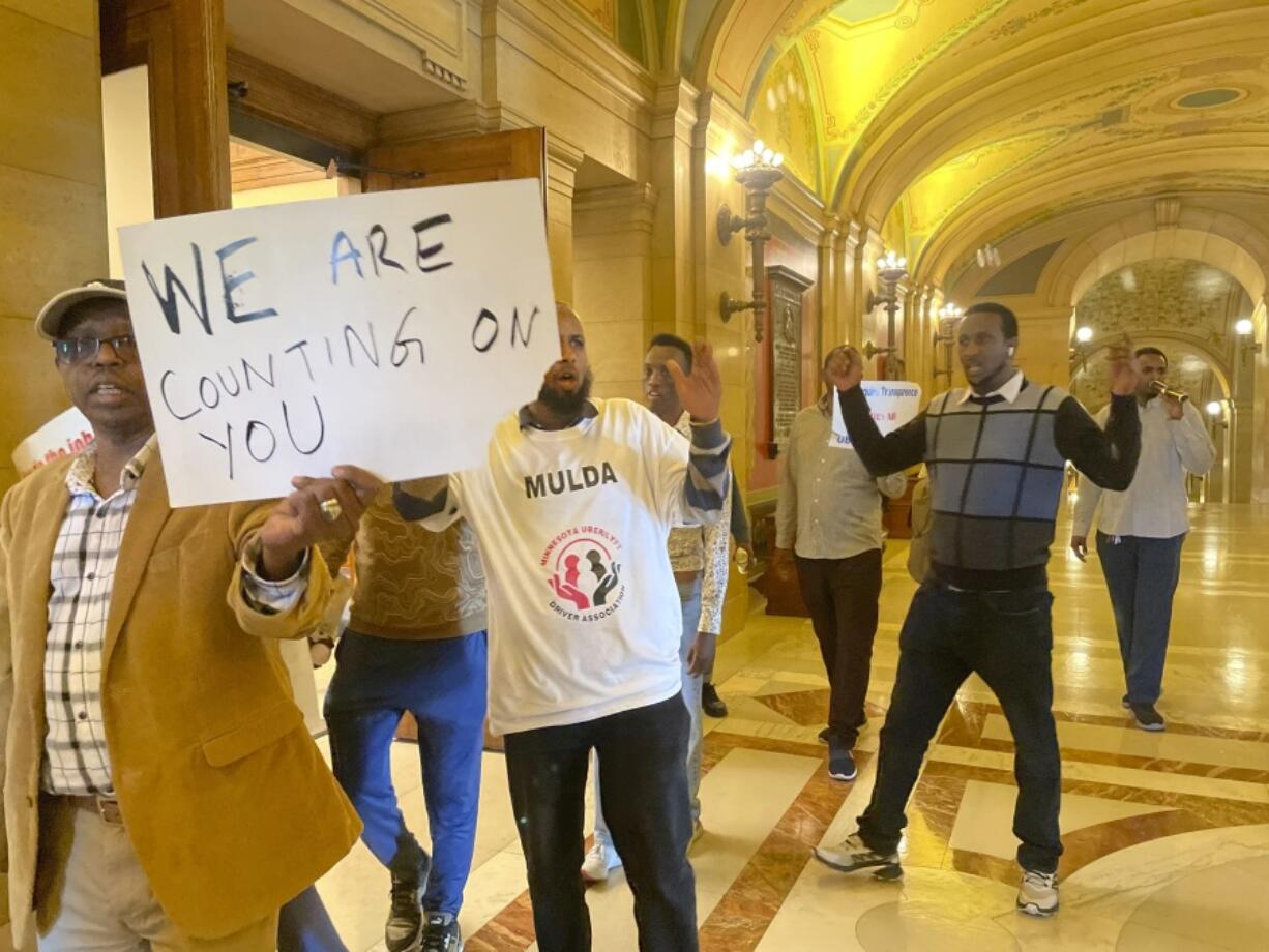 Supporters of Minnesota legislation -- which would require ride-hailing companies to increase pay for drivers -- walk through the State Capitol building, holding signs that say &ldquo;WE ARE COUNTING ON YOU&rdquo; and shirts that say &ldquo;MULDA Minnesota Uber/Lyft Driver Association,&rdquo; in St. Paul, Minn.,, May 17, 2024. Uber and Lyft have said they will leave the state if Minnesota lawmakers pass legislation that requires the companies to raise driver pay by more than they want to.
