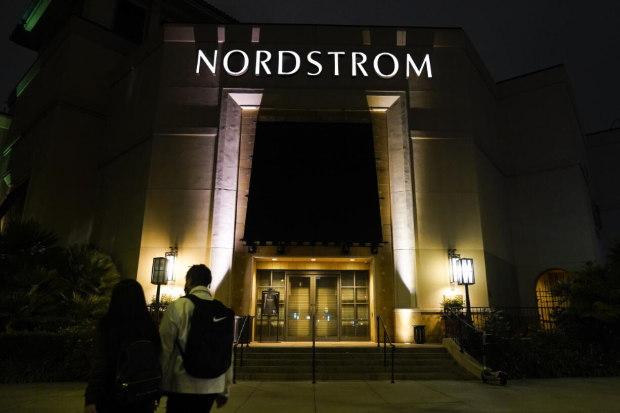 FILE - Two pedestrians walk near an entrance to a Nordstrom department store at the Grove mall in Los Angeles, Dec. 2, 2021. Bruce Nordstrom, a retail executive who helped expand his family&rsquo;s Pacific Northwest department store chain into an upscale national brand, has died. Seattle-based Nordstrom Inc. said its former chairman died at his home, Saturday, May 18, 2024. He was 90. (AP Photo/Jae C.