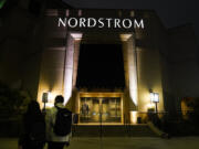 FILE - Two pedestrians walk near an entrance to a Nordstrom department store at the Grove mall in Los Angeles, Dec. 2, 2021. Bruce Nordstrom, a retail executive who helped expand his family&rsquo;s Pacific Northwest department store chain into an upscale national brand, has died. Seattle-based Nordstrom Inc. said its former chairman died at his home, Saturday, May 18, 2024. He was 90. (AP Photo/Jae C.