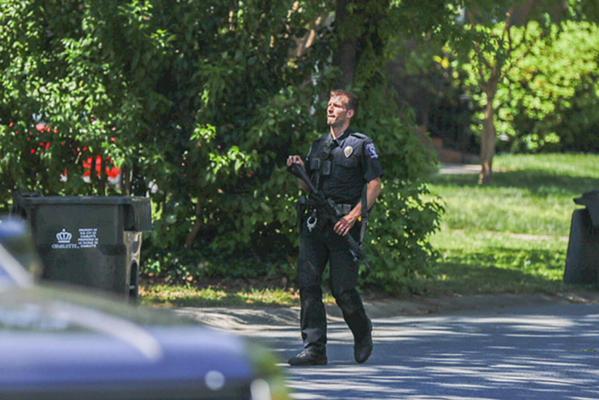 A Charlotte Mecklenburg police officer carries a gun as he walks in the neighborhood where an officer-involved shooting took place in Charlotte, N.C., Monday, April 29, 2024. Police in North Carolina say numerous law enforcement officers conducting a task force operation have been struck by gunfire in Charlotte.