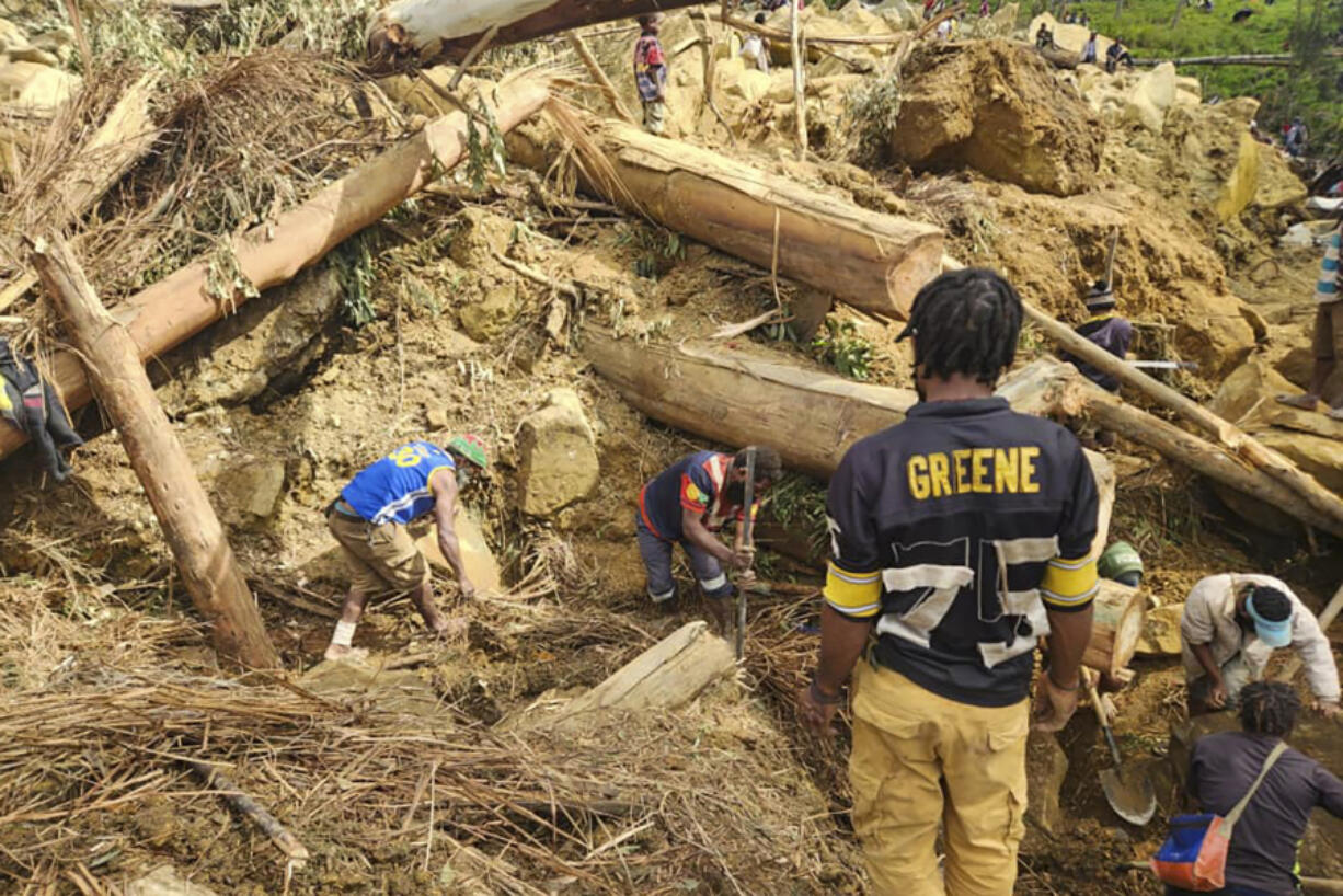 Villagers search Monday amongst the debris from a landslide in the village of Yambali in the Highlands of Papua New Guinea.