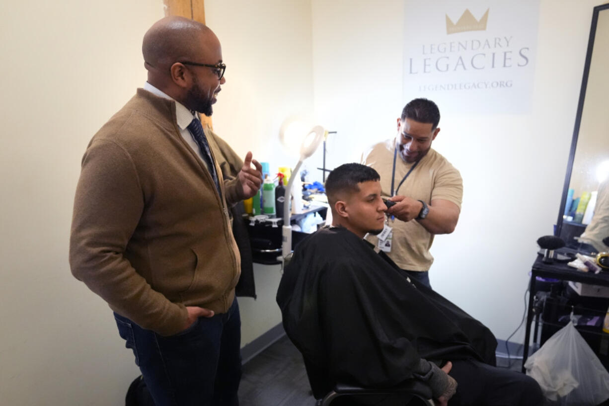 Ron Waddell, Founder and Executive Director of Legendary Legacies, left, talks with Jesus Pizarro, right, who is cutting the hair of Abrain Mendez, at his nonprofit organization, Friday, April 19, 2024, in Worcester, Mass. Waddell credits Blue Cross Blue Shield volunteers for truly investing in their employee service opportunities, which are increasing across the corporate realm.