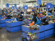 FILE - Cashiers process purchases at a Walmart Supercenter in North Bergen, N.J., on Feb. 9, 2023.