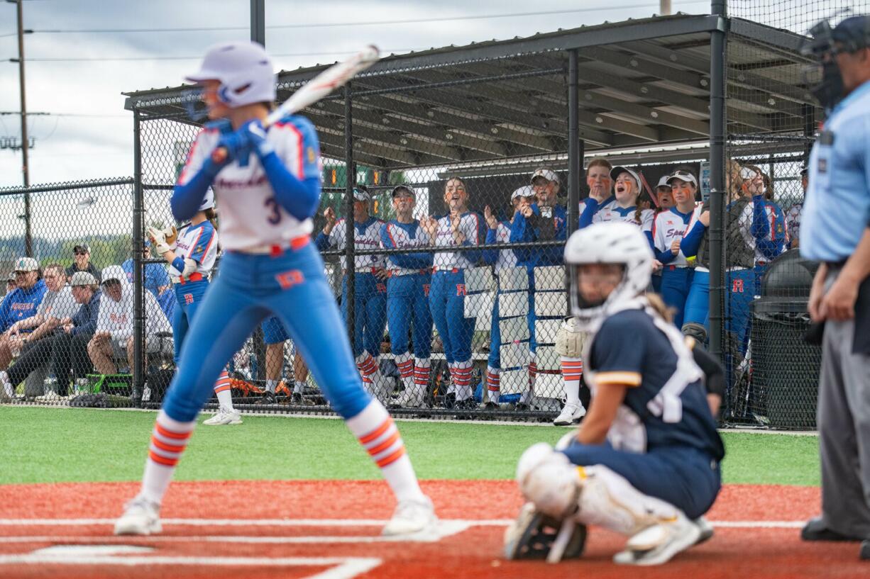 Ridgefield players cheer from the dugout as Ridgefield's Tava Whitlow (3) stands in the batter's box during the Class 2A District 4 softball tournament against Aberdeen on Thursday, May 16, 2024, in Chehalis.
