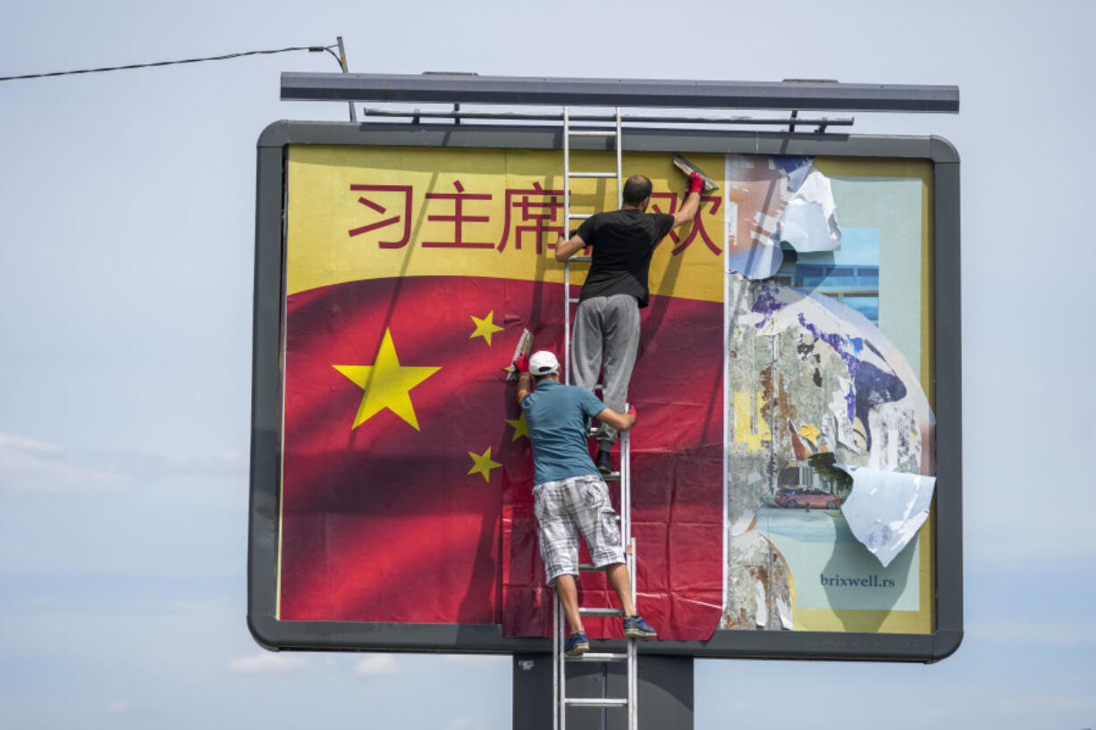 Workers stick a Chinese national flag on a billboard in Belgrade, Serbia, Tuesday, May 7, 2024. Chinese leader Xi Jinping&rsquo;s visit to European ally Serbia on Tuesday falls on a symbolic date: the 25th anniversary of the bombing of the Chinese Embassy in Belgrade during NATO&rsquo;s air war over Kosovo.