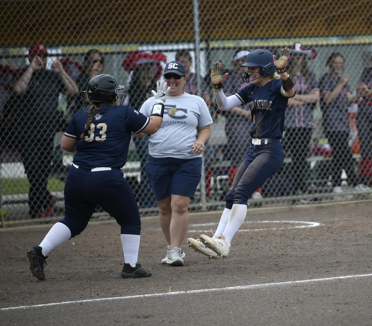 Kingsley Williams (right) celebrates her RBI single with teammate Kenzie Kuhnhausen (33) as coach Carrie Farrell looks on during Seton Catholic's 5-4 win over Riverside in the Class 1A state softball semifinals at Columbia Playfields in Richland on Friday, May 24, 2024.