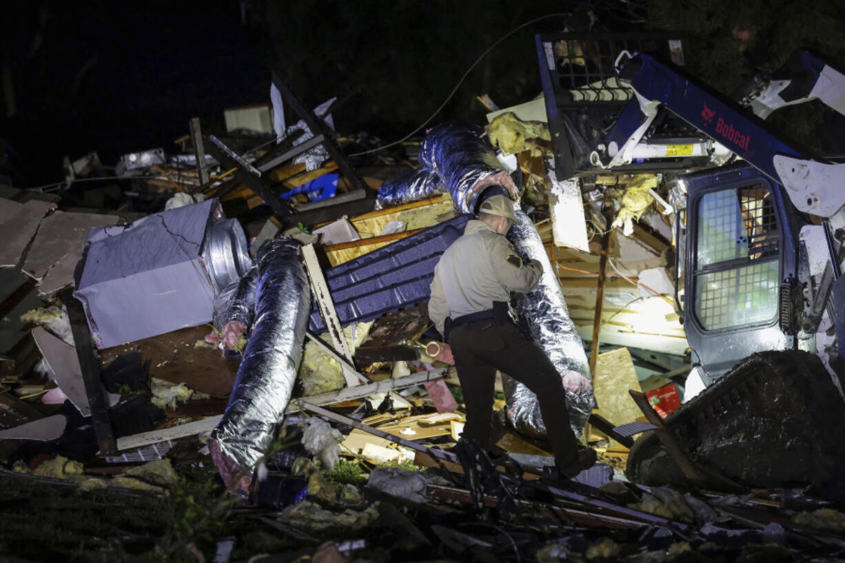 An Oklahoma State Highway Patrol trooper searches storm damage Tuesday, May 7, 2024 in Barnsdall, Okla.