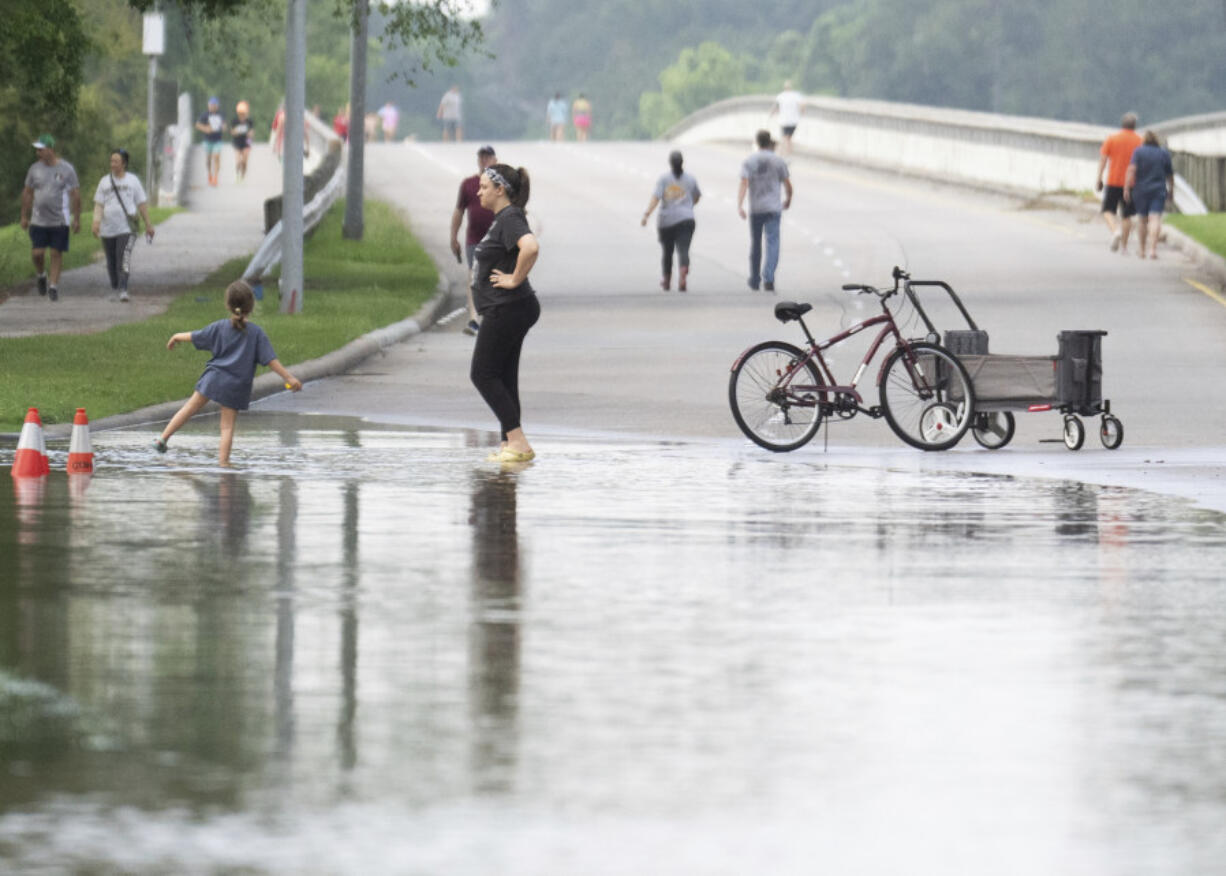 People gather to walk around bridge over Lake Houston along West Lake Houston Parkway after it was closed due to high water on either side of the thoroughfare, Saturday, May 4, 2024, in Kingwood, Texas  (Jason Fochtman/Houston Chronicle via AP)