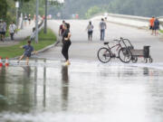 People gather to walk around bridge over Lake Houston along West Lake Houston Parkway after it was closed due to high water on either side of the thoroughfare, Saturday, May 4, 2024, in Kingwood, Texas  (Jason Fochtman/Houston Chronicle via AP)