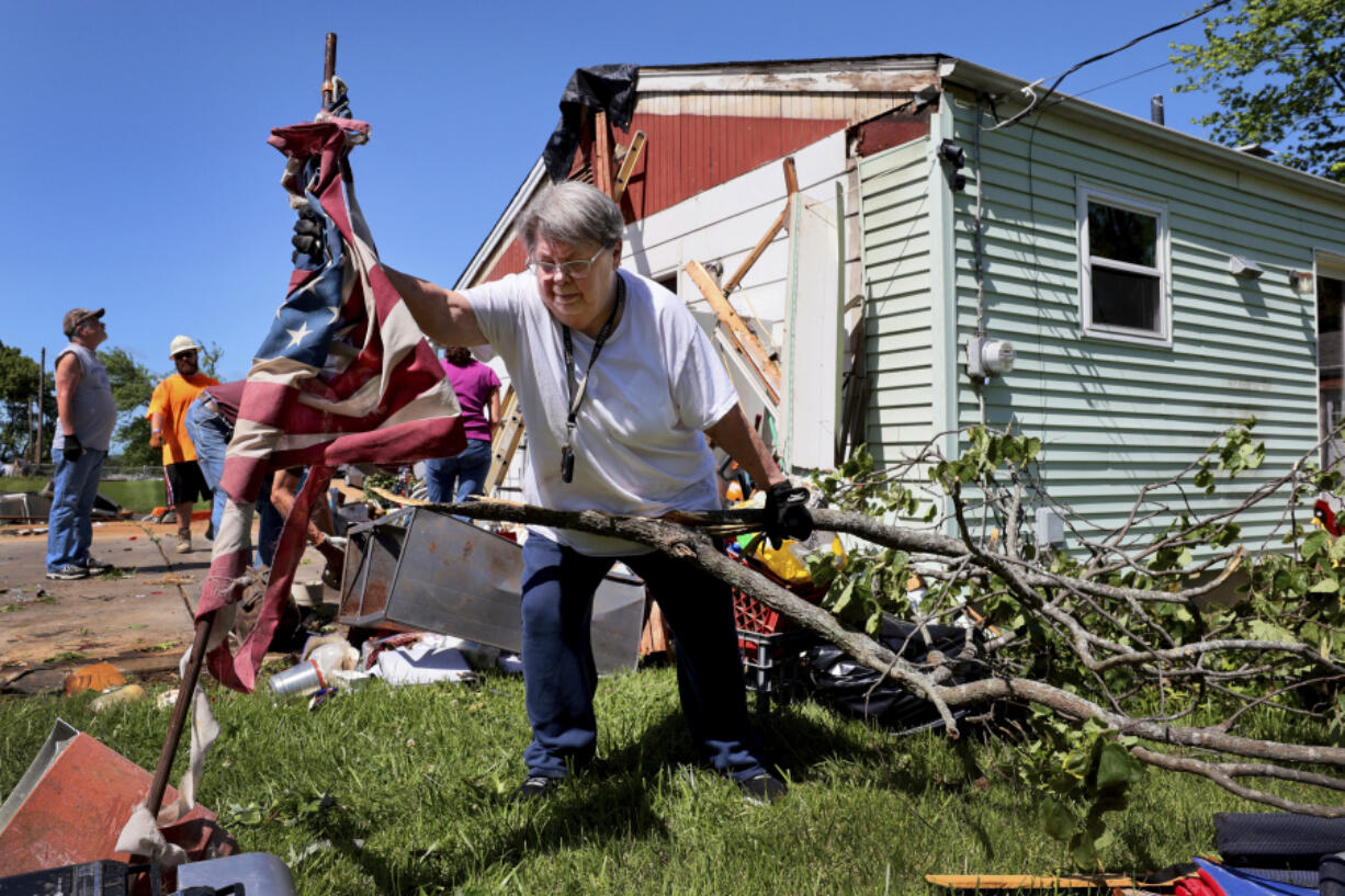 Patti Manley, 69, moves a shredded American flag as she gathers branches from the backyard of her mother&#039;s home on Morningdale Place in Mehlville, Mo. on Monday, May 27, 2024, following a violent storm and possible tornado Sunday evening. Manley was staying with her mother Jackie Moloney, 88, when the storm hit. She and her mother rode it out in an interior bathroom. (Robert Cohen/St.