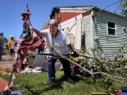 Patti Manley, 69, moves a shredded American flag as she gathers branches from the backyard of her mother&#039;s home on Morningdale Place in Mehlville, Mo. on Monday, May 27, 2024, following a violent storm and possible tornado Sunday evening. Manley was staying with her mother Jackie Moloney, 88, when the storm hit. She and her mother rode it out in an interior bathroom. (Robert Cohen/St.