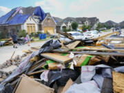 People walk through a Bridgeland neighborhood as families begin cleaning up storm damage, Sunday, May 19, 2024, in Cypress, Texas.