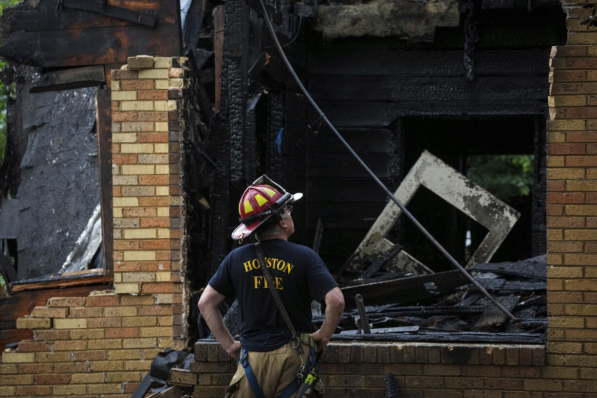 Houston Fire Department Senior Captain Chris Delbello surveys a damaged home after a fire Tuesday, May 28, 2024, in the Third Ward neighborhood in Houston. Neighbors said the house caught fire as a storm moved through the area.