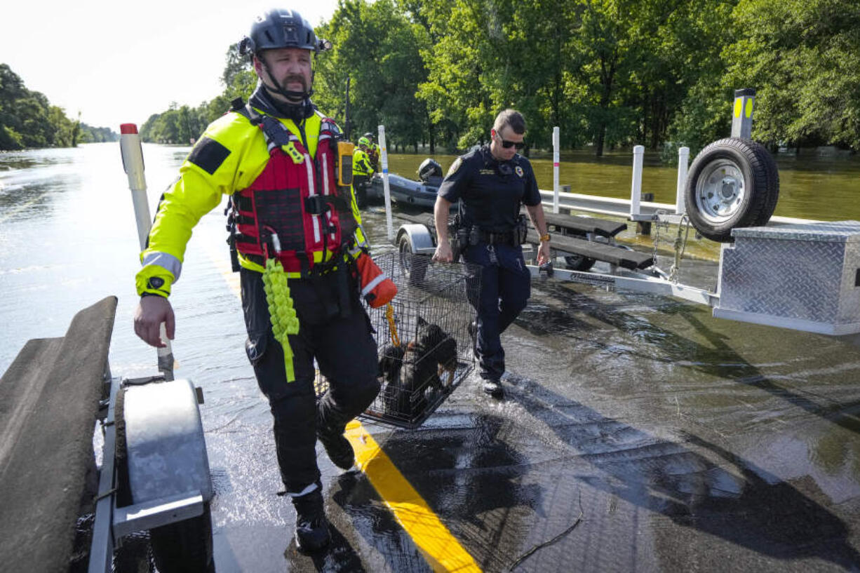 The Conroe firefighters with CFD&rsquo;s Rapid Intervention Team carry a pair of dogs rescued in a boat in the aftermath of a severe storm, Thursday, May 2, 2024, in Conroe, Texas.