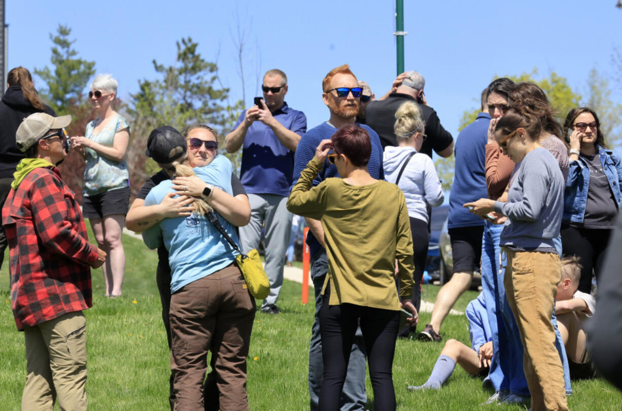 People gather at a site designated for parent and student reunifications following a report of a armed person outside Mount Horeb Middle School in Mount Horeb, Wis., Wednesday, May 1, 2024.