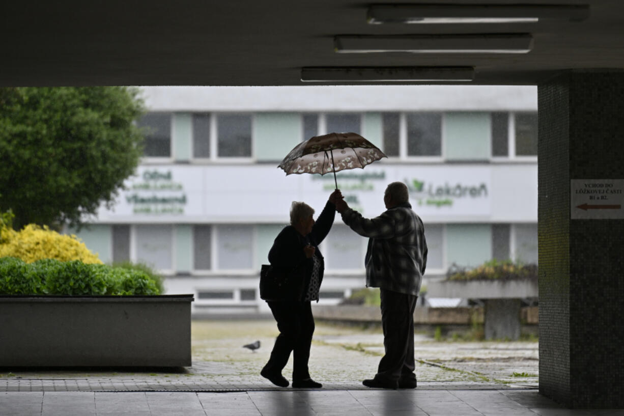 An old couple hold an umrella outside the F. D. Roosevelt University Hospital, where Slovak Prime Minister Robert Fico, who was shot and injured, is being treated, in Banska Bystrica, central Slovakia, Friday, May 17, 2024. Fico, 59, was shot multiple times on Wednesday as he was greeting supporters after a government meeting in the former coal mining town of Handlova. Officials at first reported that doctors were fighting for his life but after a five-hour operation described his situation as serious but stable.