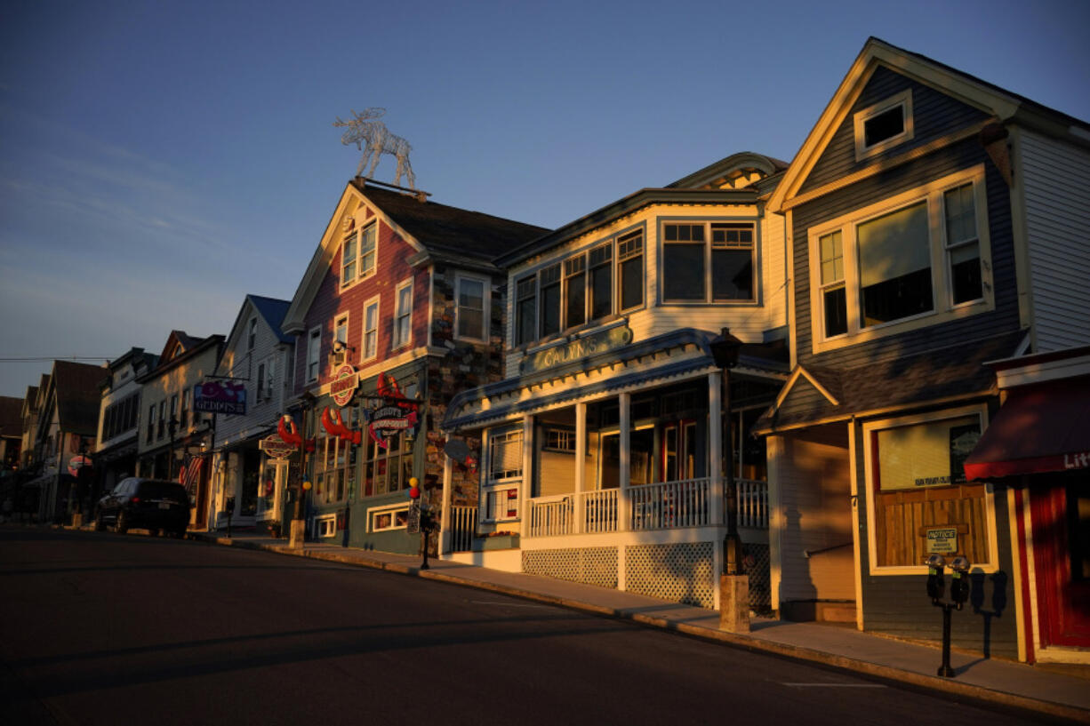 File - Early-morning light shines on shops on Main Street, June 11, 2022, in Bar Harbor, Maine.  With stubborn inflation and higher costs, layoffs at small businesses are sometimes a necessity. U.S.-based employers announced 64,789 cuts in April, down 28% from 90,309 cuts announced in March, according to a report by global outplacement and business and executive coaching firm Challenger, Gray &amp; Christmas, Inc. (AP Photo/Robert F.