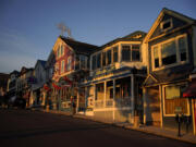 File - Early-morning light shines on shops on Main Street, June 11, 2022, in Bar Harbor, Maine.  With stubborn inflation and higher costs, layoffs at small businesses are sometimes a necessity. U.S.-based employers announced 64,789 cuts in April, down 28% from 90,309 cuts announced in March, according to a report by global outplacement and business and executive coaching firm Challenger, Gray &amp; Christmas, Inc. (AP Photo/Robert F.