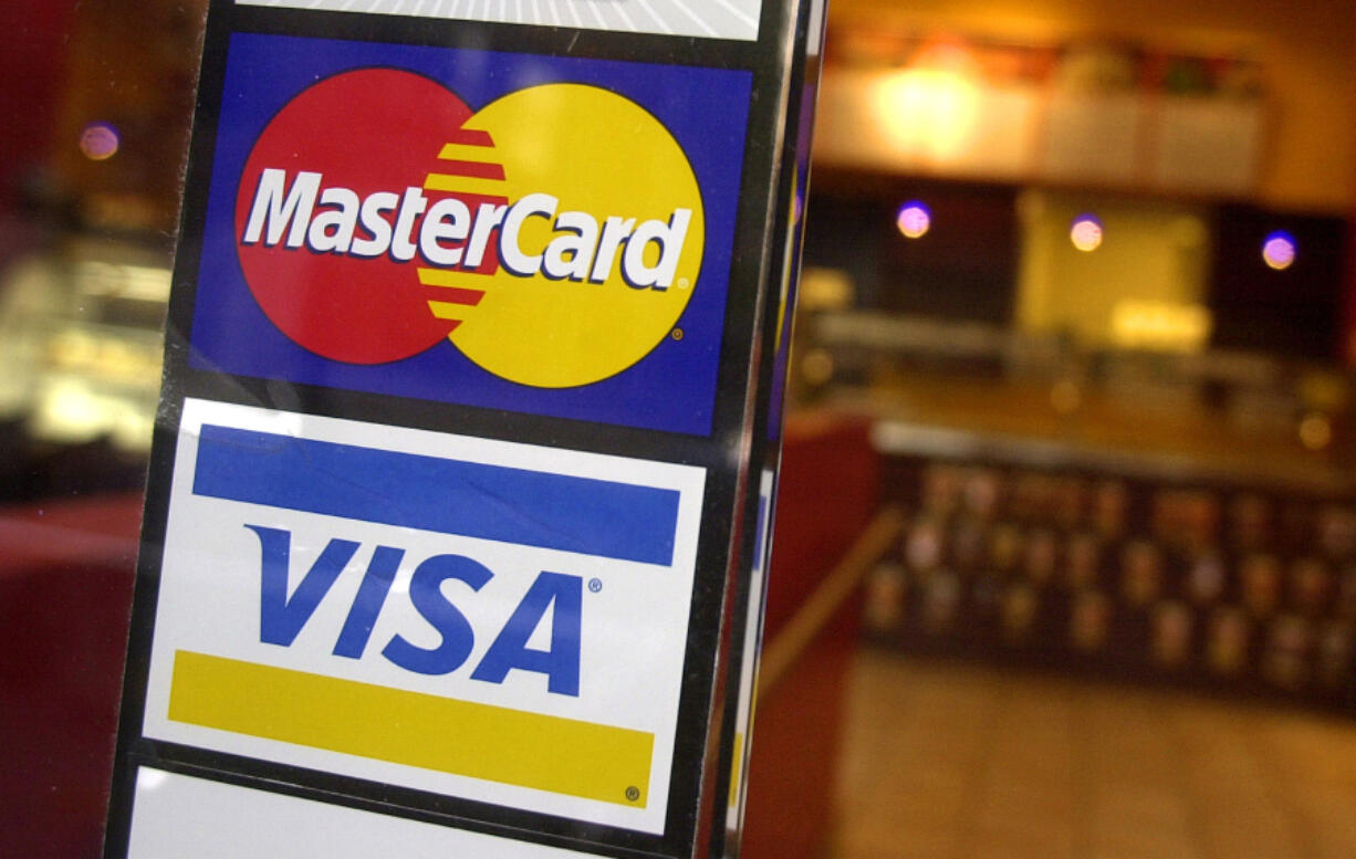 FILE - MasterCard and Visa credit card logos are shown at the entrance of a New York coffee shop, April 22, 2005. A deadline is looming for millions of businesses who may be entitled to a payout in a $5.5 billion antitrust settlement with Visa and Mastercard. The settlement stems from a 2005 lawsuit that alleged merchants paid excessive fees to accept Visa and Mastercard credit cards, and that Visa and Mastercard and their member banks acted in violation of antitrust laws.