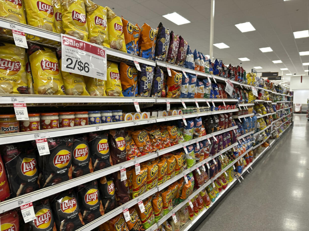 FILE - Sale signs hang on the long display of snacks at a Target store Oct. 4, 2023, in Sheridan, Colo.