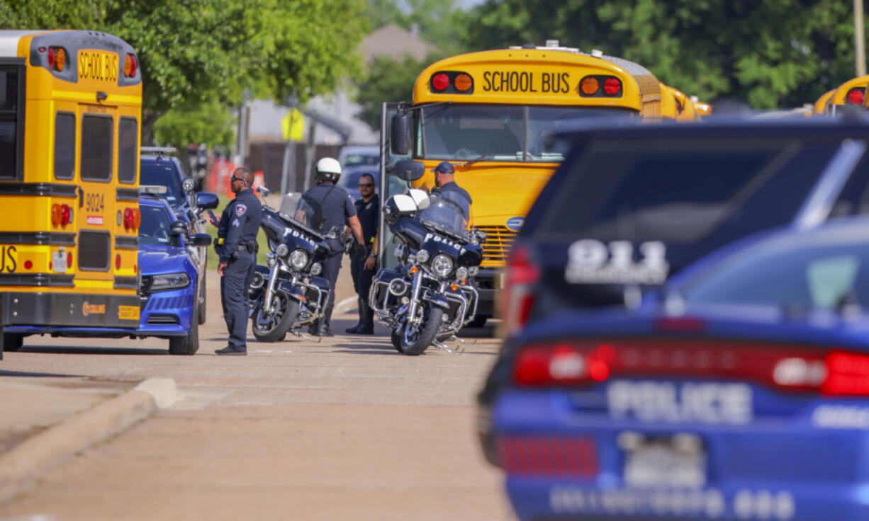 Police officers prepare to escort students to be reunited with their families at Arlington Bowie High School after the school was placed on a lockdown due to a suspected shooting outside the school building, Wednesday April 24, 2024, in Arlington, Texas.