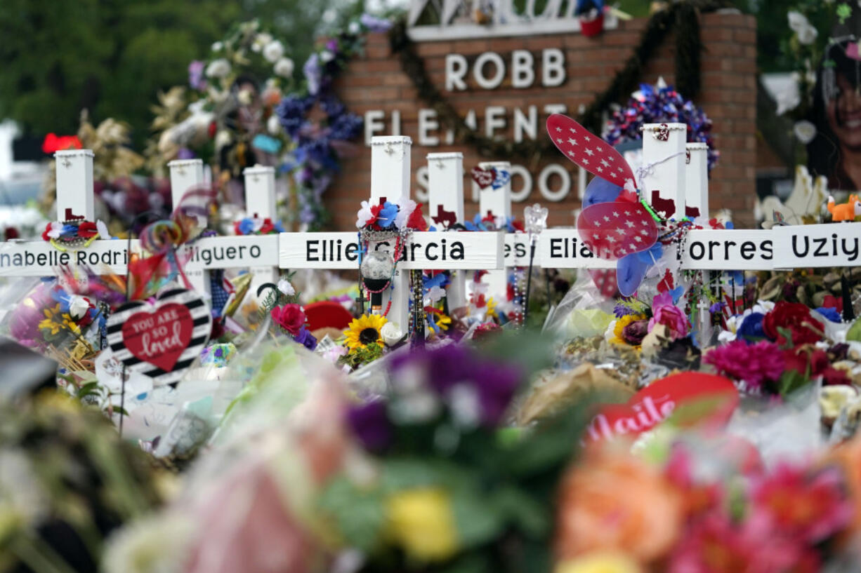 FILE - Crosses are surrounded by flowers and other items at a memorial, Thursday, June 9, 2022, for the victims of a shooting at Robb Elementary School in Uvalde, Texas. The families of 19 people who were killed or injured in the shooting and their attorneys are set to make an announcement, Wednesday, May 22, 2024. Friday will mark the two-year anniversary of the shooting where a gunman killed 19 students and two teachers.