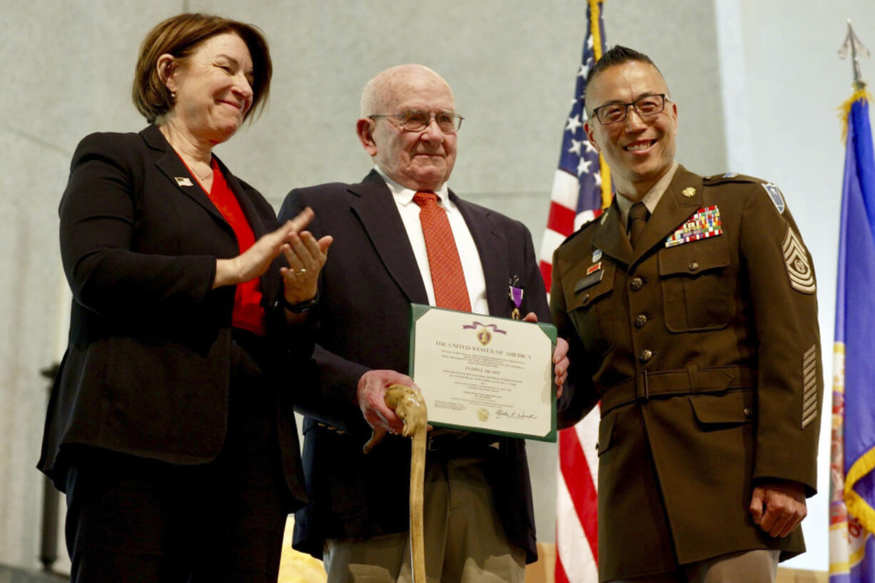 U.S. Sen. Amy Klobuchar. D-Minn., and Command Sgt Maj. Jason Rost of the Minnesota National Guard present a Purple Heart to Earl Meyer for combat injuries he received while serving in the Korean War during a ceremony Friday in St. Peter, Minn.