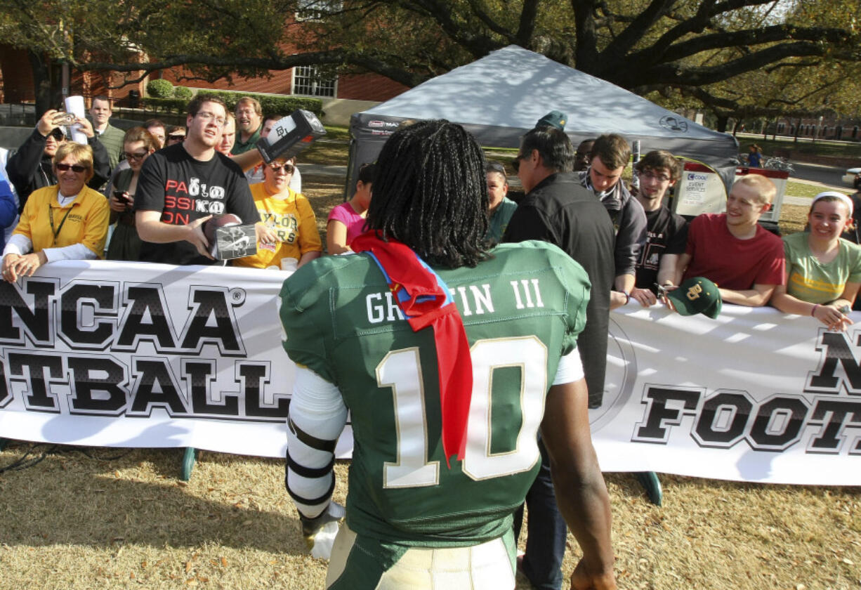 Heisman Trophy winner and former quarterback Robert Griffin III walks over to fans Feb. 27, 2012, on the Baylor University campus where he was at a photo session for the EA Sports NCAA Football 13 video game to be released in July.