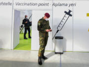 FILE - A soldier of the German Armed Forces Bundeswehr stands inside a new vaccination centre at the former Tempelhof airport in Berlin, Germany, before its opening on Monday, March 8, 2021. Germany has scrapped a requirement for its military servicepeople to be vaccinated against COVID-19. Members of the German military, the Bundeswehr, are required to get vaccinations against a number of diseases &mdash; including measles, mumps and flu. COVID-19 was added to the list in November 2021, meaning that anyone who refused to get vaccinated against it could face disciplinary measures.