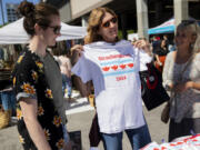 Mary Beth McCarthy, center, holds a Cicadapalooza shirt sold by Trayce Zimmermann at her self-described &ldquo;cicada chic&rdquo; apparel booth on May 25, at the Randolph Street Market in Chicago.