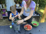 Grow It organizer Leah Reichardt-Osterkatz, right, helps children make smoothies from strawberries they picked, plus kale grown on the farm May 29 at Spring Forest in Hillsborough, N.C.