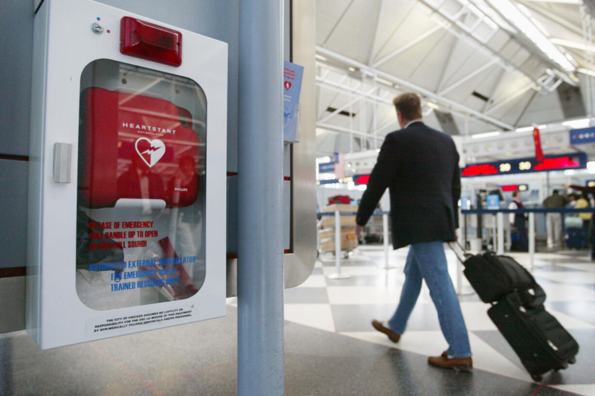 A traveler passes an Automated External Defibrillator in Terminal 1 Nov. 12, 2003, at O&rsquo;Hare International Airport in Chicago. An Automated External Defibrillator (AED) is a user-friendly device that when used properly on a person suffering a sudden cardiac arrest administers an electric shock to the heart. Its built-in microprocessor then assesses the patient&rsquo;s heart rhythm, judging whether more defibrillation would be needed. The Chicago Airport System implemented the first public-access defibrillation program at all its airports, including O&rsquo;Hare International Airport. Defibrillators are strategically located throughout the airport terminals within a one-minute walk from any point in the airport. The units are in cabinets that are directly linked to the City of Chicago&rsquo;s emergency medical services.