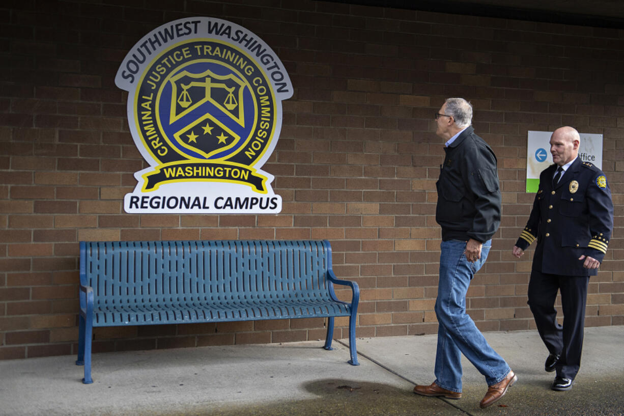 Gov. Jay Inslee, left, and Commissioner Dave Miller of the Criminal Justice Training Commission walk past the logo for Clark County&rsquo;s law enforcement academy in east Vancouver on opening day in January.