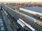 In an aerial view, freight rail cars sit in a rail yard near shipping containers on Nov. 22, 2022, in Wilmington, California.