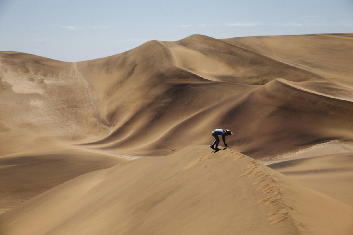 A Namibian child, part of a group of tourists on a desert day tour, plays on sand dunes in the desert area of the Dorob National Park, part of the Namib desert, on Feb. 17, 2016, on the outskirts of Swakopmund, Namibia.