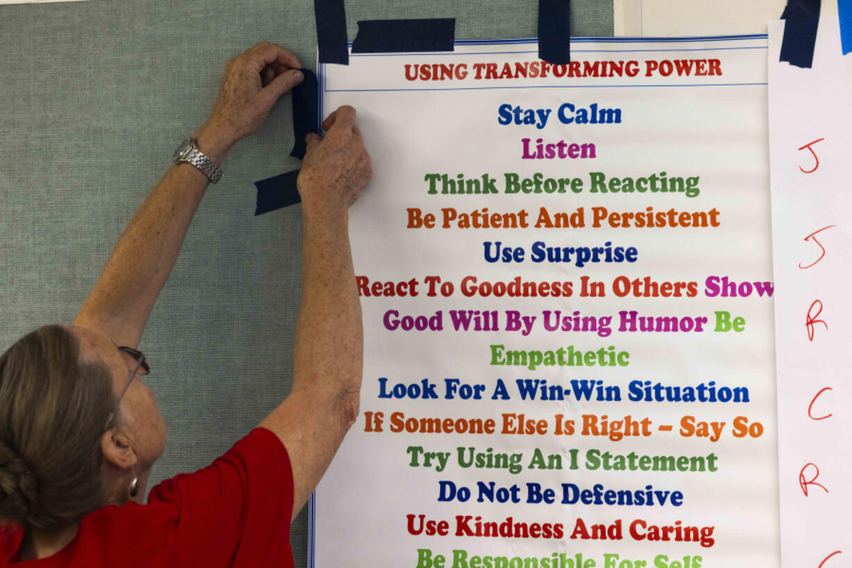 Alternative to Violence Project facilitator June Thomasson tapes up a poster at Evergreen High School in Seattle.