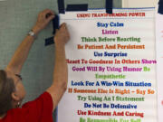 Alternative to Violence Project facilitator June Thomasson tapes up a poster at Evergreen High School in Seattle.