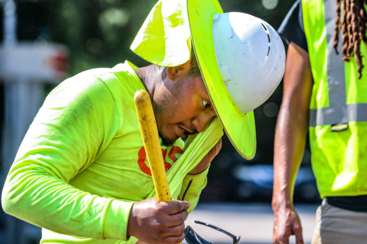 Fernando Rosales with RJH electrical contractors worked on installing an electrical box on Northside Drive near I-75 as he wiped away the sweat from the oppressive heat in metro Atlanta on Aug. 14, 2023.